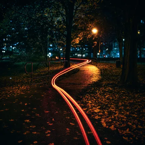 Looping streaks of light from a bicycle lamp drawn through a dark, empty park.